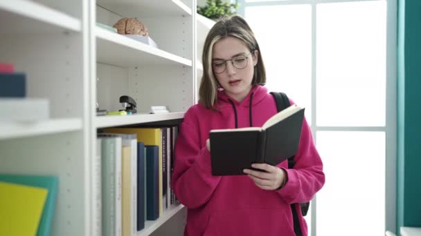 Young Blonde Woman Student Reading Book Doing Silence Gesture Library — Vídeo de Stock