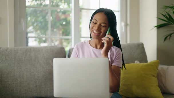 Mujer Afroamericana Usando Portátil Hablando Teléfono Inteligente Casa — Vídeos de Stock