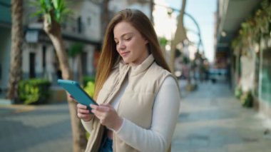 Sokakta dokunmatik ped kullanan kendine güvenen genç sarışın kadın.