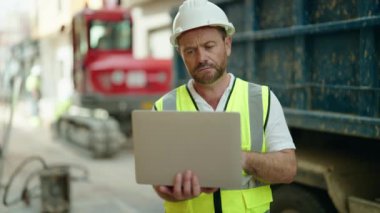 Middle age man architect using laptop at street