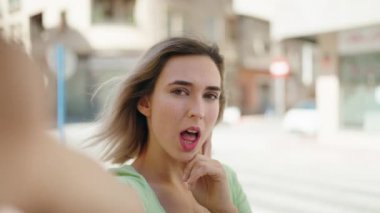 Genç bir kadın, kendinden emin gülümsüyor. Kameranın karşısında özçekim yapıyor.