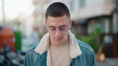 Young hispanic man with relaxed expression standing at street