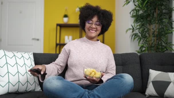 Młoda Afroamerykanka Ogląda Telewizję Siedzącą Kanapie Jedzącą Frytki Domu — Wideo stockowe