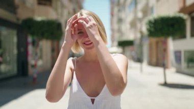 Young blonde woman smiling confident walking at street
