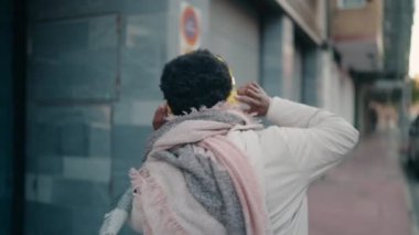 Genç Afrikalı Amerikalı kadın müzik dinliyor ve sokakta dans ediyor.