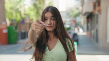 Genç, güzel İspanyol kadın gülümsüyor kendinden emin bir şekilde sokakta el kol geziyor.