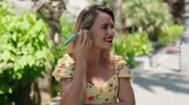 Young beautiful hispanic woman miling confident listening audio message by the smartphone at park