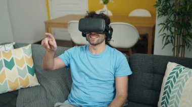 Evde sanal gerçeklik gözlüğü kullanarak video oyunu oynayan İspanyol genç adam.