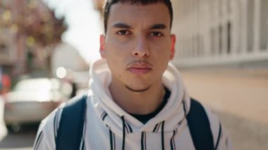 Young man student smiling confident standing with arms crossed gesture at street