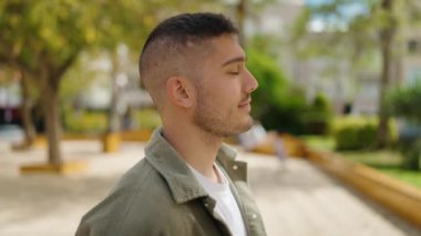 Parkta kendinden emin gülümseyen İspanyol genç adam.