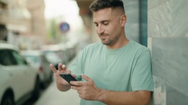 Sokakta akıllı telefon kullanan, kendine güvenen genç bir İspanyol.