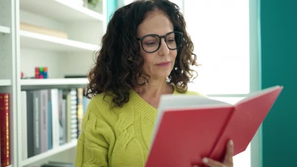 Middle Age Hispanic Woman Teacher Smiling Confident Reading Book Library — Stok video