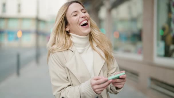 Junge Blonde Frau Lächelt Selbstbewusst Mit Smartphone Auf Der Straße — Stockvideo