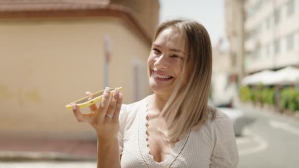 年轻的高加索女人在街上用智能手机自信地微笑着 — 图库视频影像