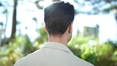 Genç İspanyol adam gülümsüyor parkın kenarına bakıyor.