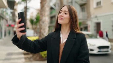 Genç İspanyol kadın gülümsüyor. Kendine güveni tam. Sokakta akıllı telefonun yanında selfie çekiyor.