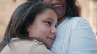 Anne ve kızı gülümsüyor, sokakta birbirlerine sarılıyorlar.