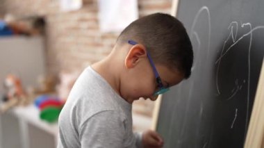 Sevimli İspanyol çocuk. Anaokulunda tahtaya çizdiği özgüvenle gülümsüyor.