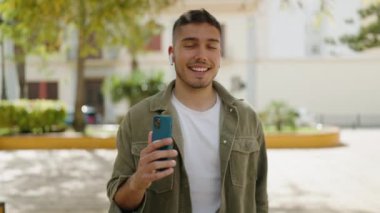 Young hispanic man smiling confident listening to music at park