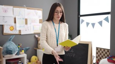 Anaokulunda durup hikaye kitabı okuyan güzel İspanyol bir anaokulu öğretmeni.