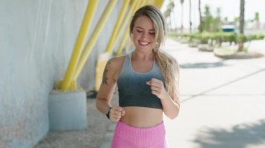 Sokakta koşan ve kronometre arayan genç sarışın kadın.