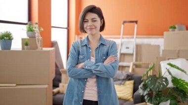 Beyaz bir kadın gülümsüyor. Yeni evinde kollarını kavuşturmuş duruyor.