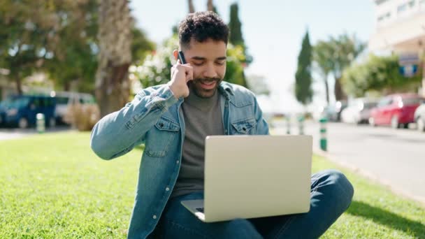 Hombre Árabe Joven Usando Ordenador Portátil Hablando Teléfono Inteligente Parque — Vídeos de Stock