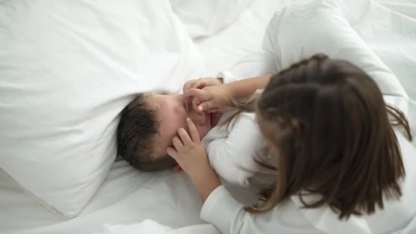 可爱的女孩和男孩躺在卧房床上打斗 — 图库视频影像