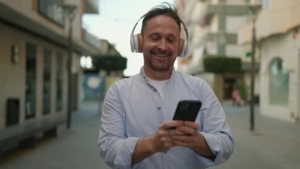 Νεαρός Καυκάσιος Άντρας Χαμογελάει Αυτοπεποίθηση Ακούγοντας Μουσική Στο Δρόμο — Αρχείο Βίντεο