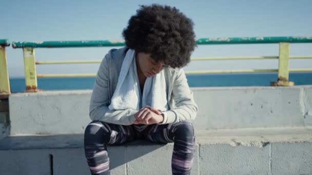 Afroamerikanerin Sitzt Mit Stoppuhr Auf Bank Meer — Stockvideo