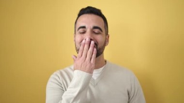 İzole edilmiş sarı arka planda kendine güvenen genç İspanyol adam gülümsüyor.