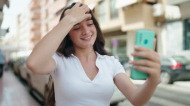 Young hispanic woman smiling confident having video call at street
