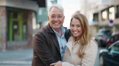 Middle age couple couple smiling confident hugging each other at street