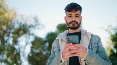 Parkta akıllı telefon kullanan ciddi yüzlü İspanyol bir genç.