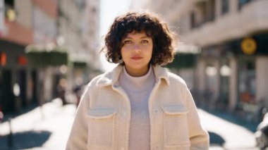 Young hispanic woman smiling confident doing ok sign with thumb up at street