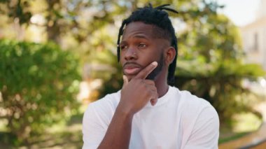 Afro-Amerikalı kadın parkta şüpheli bir ifadeyle duruyor.