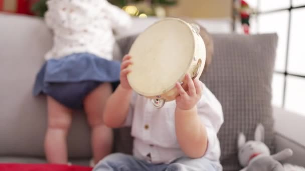 Förtjusande Barn Som Håller Tamburin Sittandes Soffan Vid Julgranen Hemma — Stockvideo