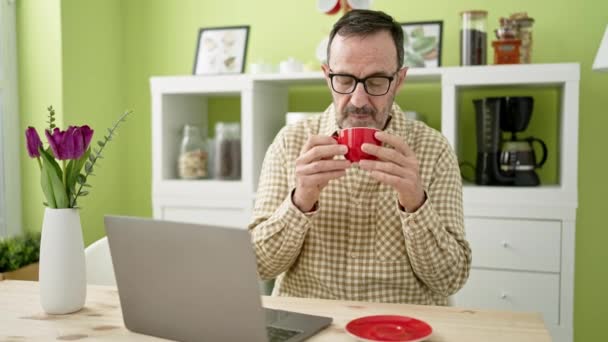 Μεσήλικας Που Χρησιμοποιεί Φορητό Υπολογιστή Πίνοντας Καφέ Στο Σπίτι — Αρχείο Βίντεο