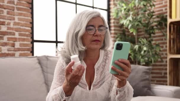Middle Age Grey Haired Woman Using Smartphone Holding Pills Home — Stock video