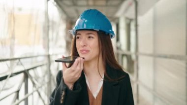 Young hispanic woman architect talking on the smartphone at street