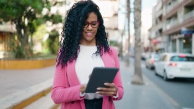 Afrikalı Amerikalı kadın yönetici parkta dokunmatik ped kullanarak gülümsüyor.