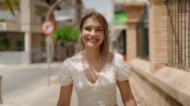 Sokakta kendine güvenen beyaz bir kadın gülümsüyor.