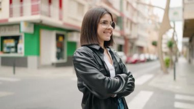Young hispanic woman standing with serious expression at street