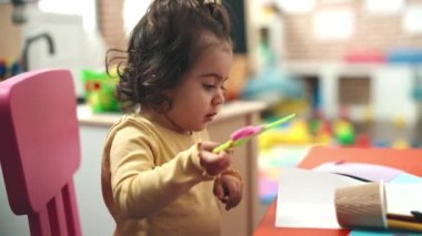 Anaokulunda elinde makas tutan sevimli İspanyol kız öğrenci.