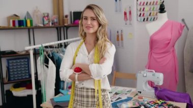 Young blonde woman tailor smiling confident standing with arms crossed gesture at tailor shop