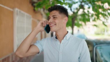 Genç İspanyol adam gülümsüyor. Kendine güveniyor. Sokakta akıllı telefondan konuşuyor.