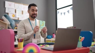 Anaokulunda öğretmenlik yapan Latin kökenli genç bir adam online kelime dersi veriyor.