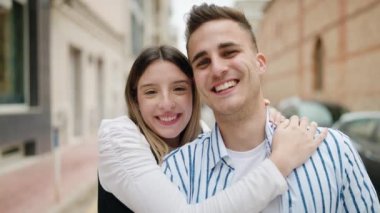 Man and woman couple hugging each other kissing at street