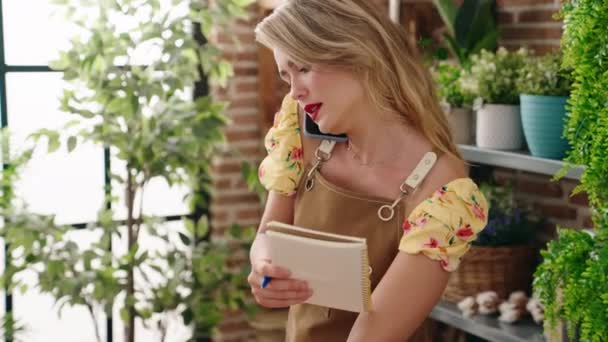 Young Beautiful Hispanic Woman Florist Talking Smartphone Writing Notebook Flower — Stock video