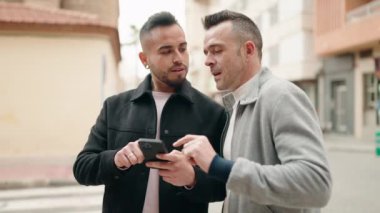 Young couple smiling confident using smartphone at street